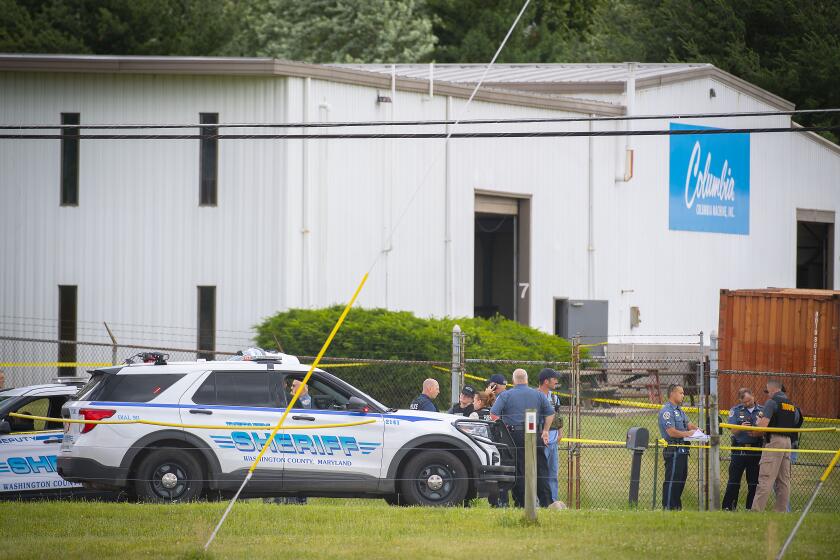Law enforcement officials stand near the scene of a shooting at Columbia Machine, Inc., in Smithsburg, Md.