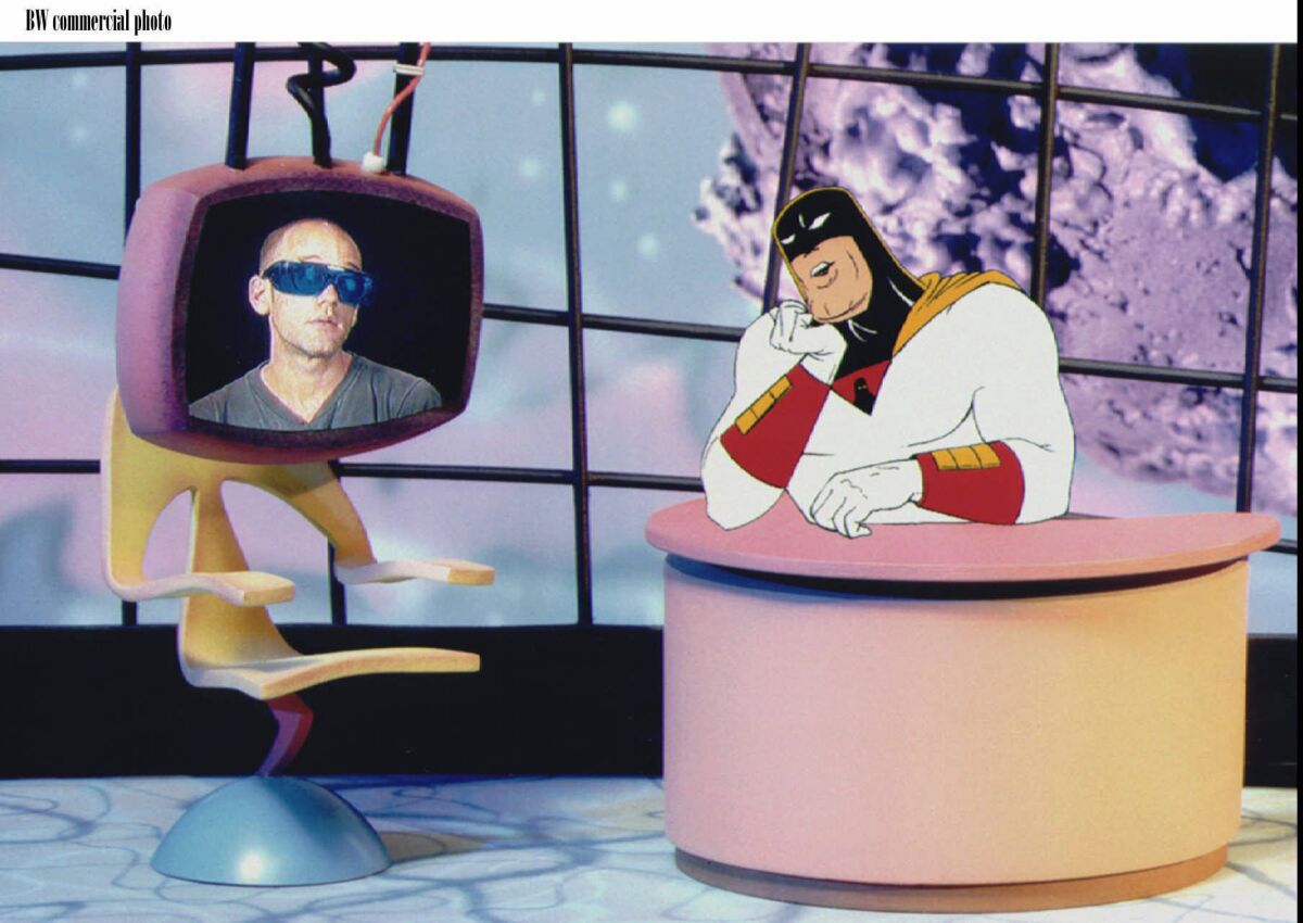 A cartoon character speaks to a live-action image of Michael Stipe appearing in a TV monitor.