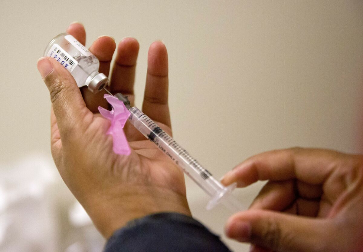 Close-up of a syringe being used to draw flu vaccine from a vial