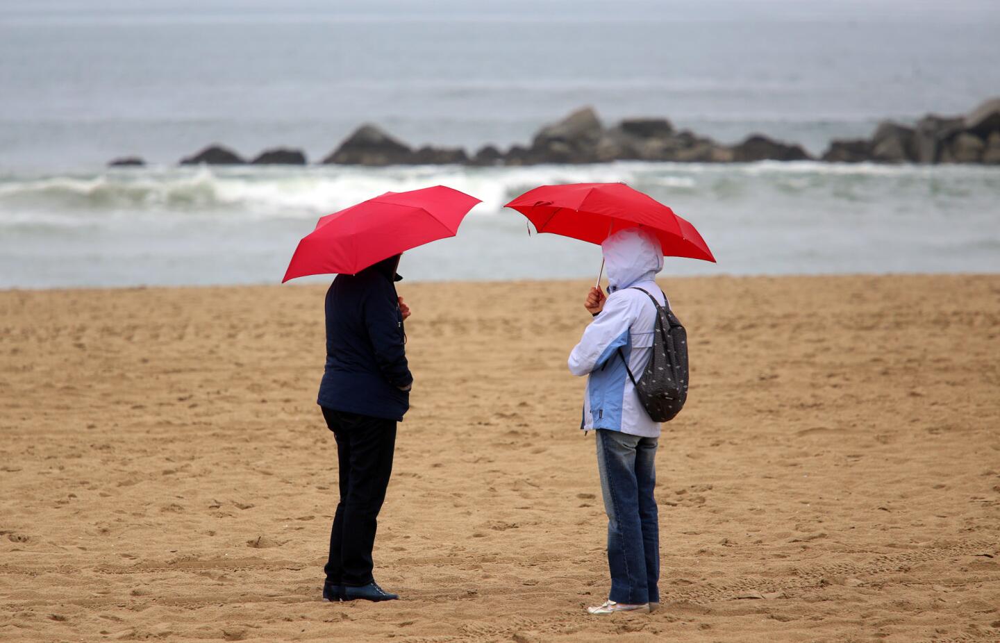 Rosa Angela Paradiso, left, and her sister Maria Paradiso, from Italy, spend a moment in the rain on Venice Beach.
