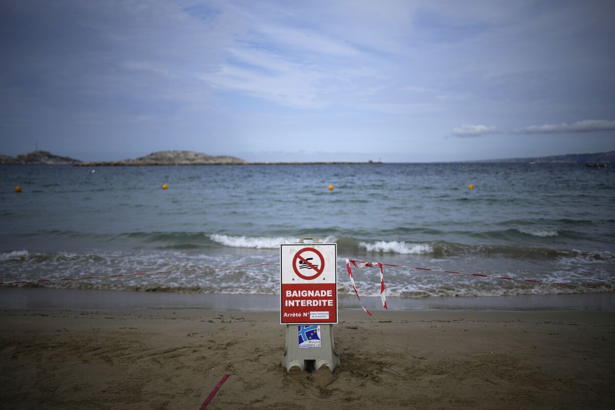 Un cartel anuncia que está prohibido entrar a nadar en la playa tras el paso de una tormenta en Marsella, Francia, el jueves 18 de agosto de 2022. (AP Foto/Daniel Cole)