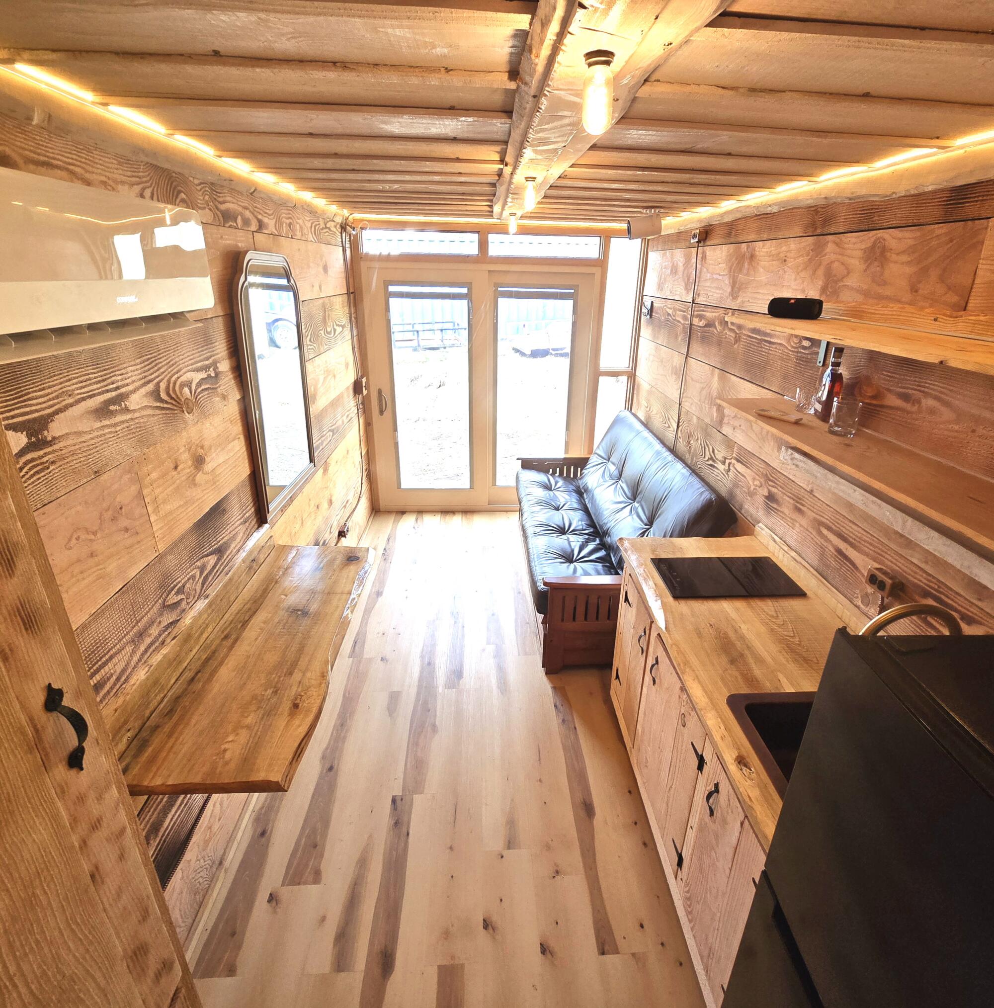 Ark Container Homes are lined with wood and fitten with a glass door at one end.