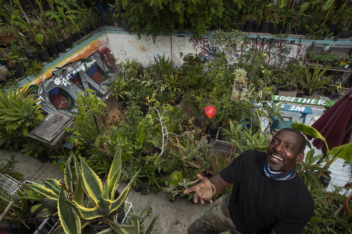 Ron Finley tosses a nectarine he grew in his West Adams backyard by the pool he filled with succulents, vegetables and herbs.