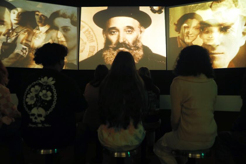 LOS ANGELES-CA-MARCH 9, 2023: Visitors watch a film at the Museum of Tolerance on March 9, 2023. (Christina House / Los Angeles Times)