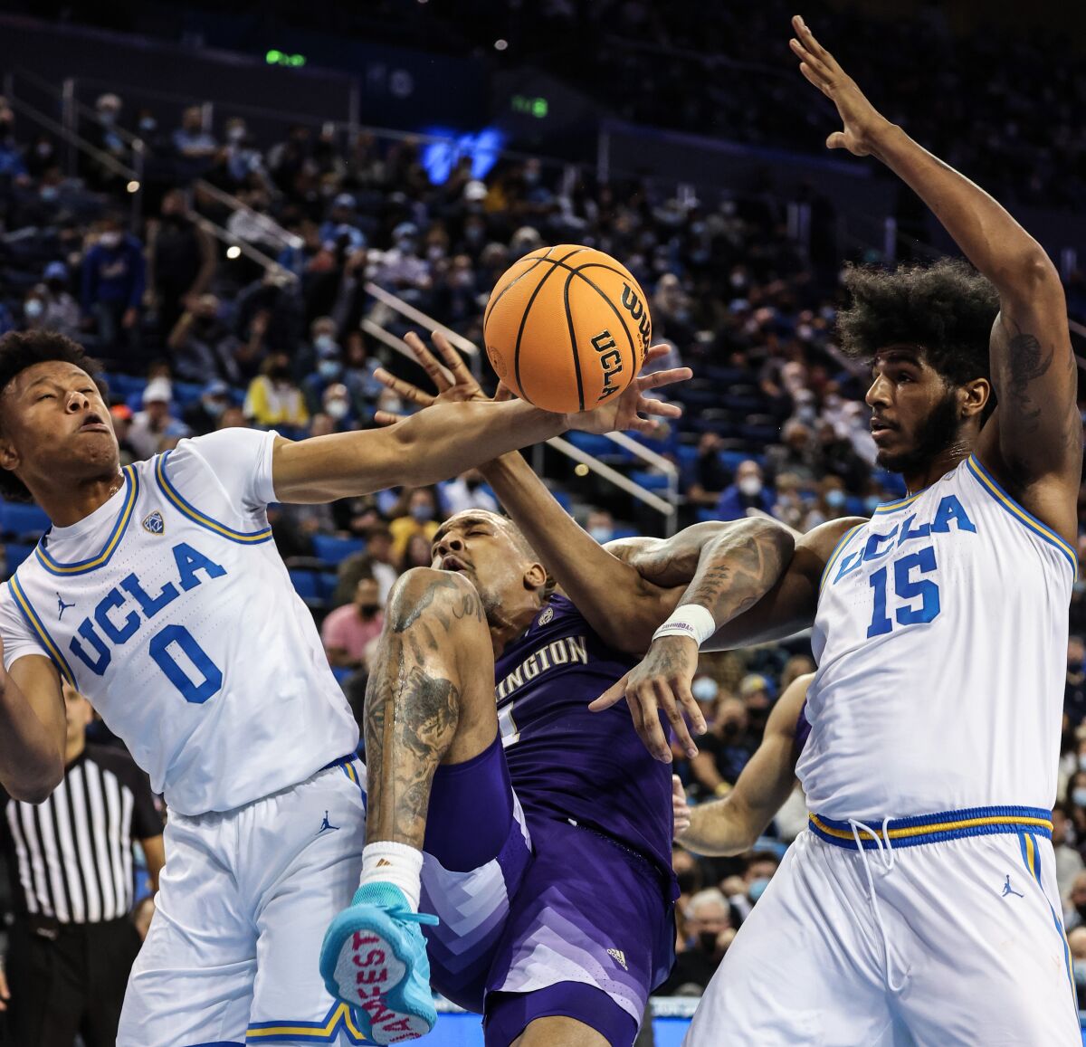 Washington forward Nate Roberts, center, battles for a rebound with UCLA guard Jaylen Clark and center Myles Johnson.