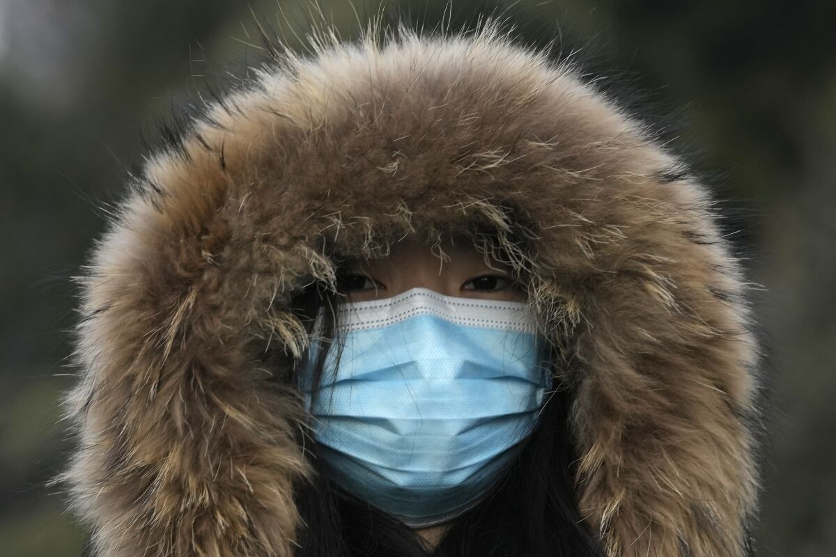 A woman wearing a mask to curb the spread of the coronavirus walks along a street in Beijing, China, Tuesday, Jan. 4, 2022. (AP Photo/Ng Han Guan)