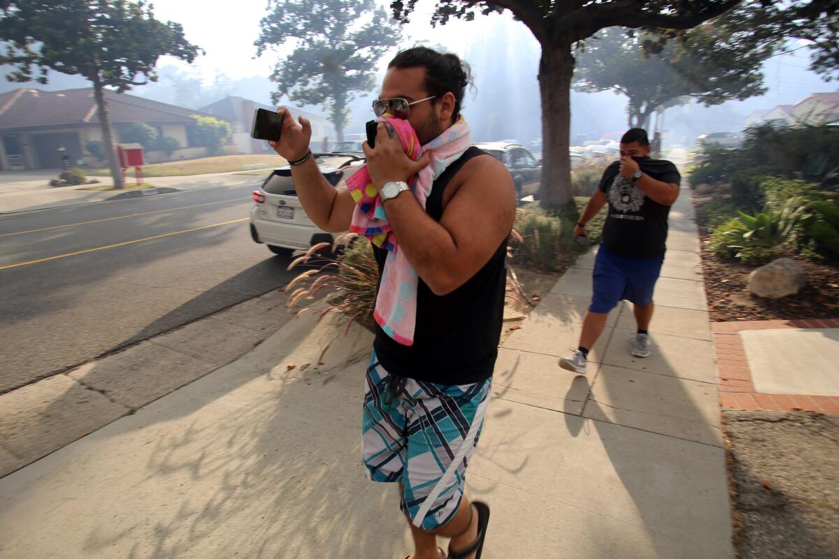 Residents cover their faces as a brush fire burns in the hills in the Glenoaks Canyon area in Glendale.