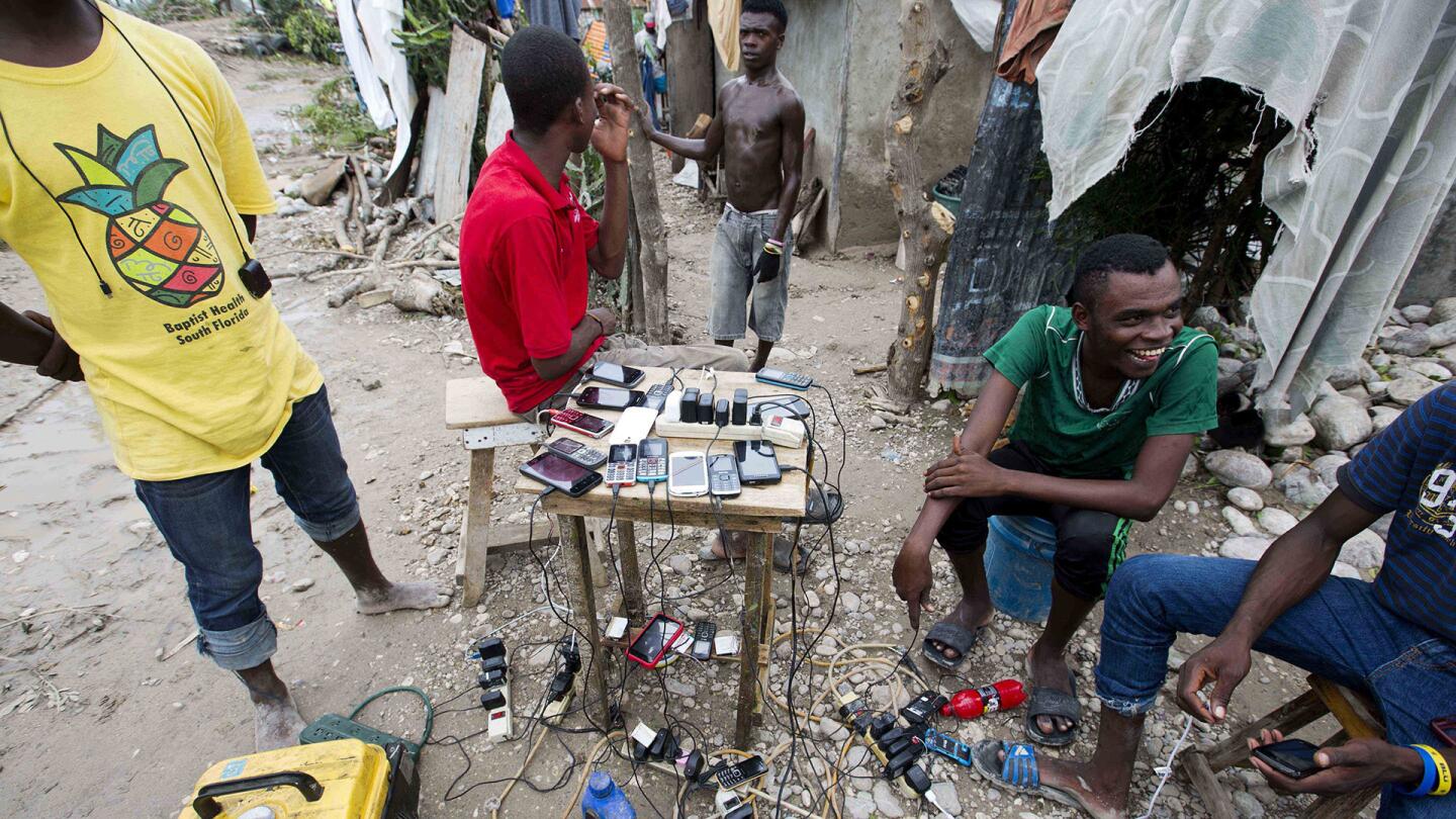 Residents charge their mobile phones for a small fee from a man with a portable generator, after all the power lines were destroyed by Hurricane Matthew in Les Cayes, Haiti, on Oct. 6, 2016.