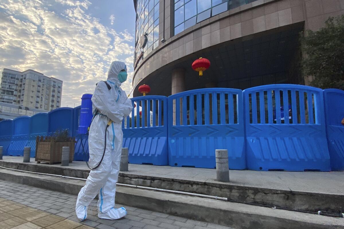 A worker in protective overalls carries disinfecting equipment outside the Wuhan Central Hospital.