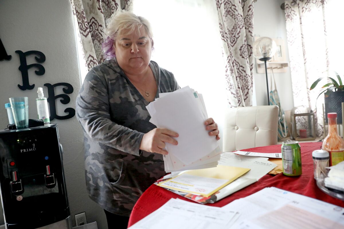 A woman holds up documents at a dining table.