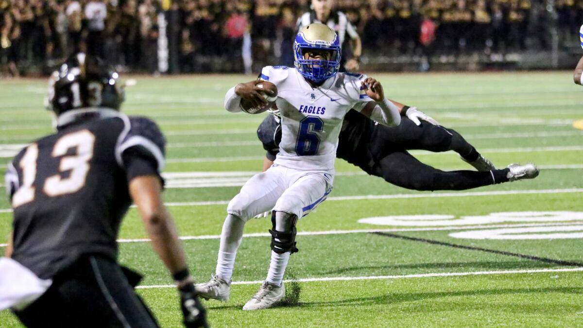 Santa Margarita quarterback Josiah Norwood tries to shake off a flying tackle attempt by a JSerra defender on Friday night.