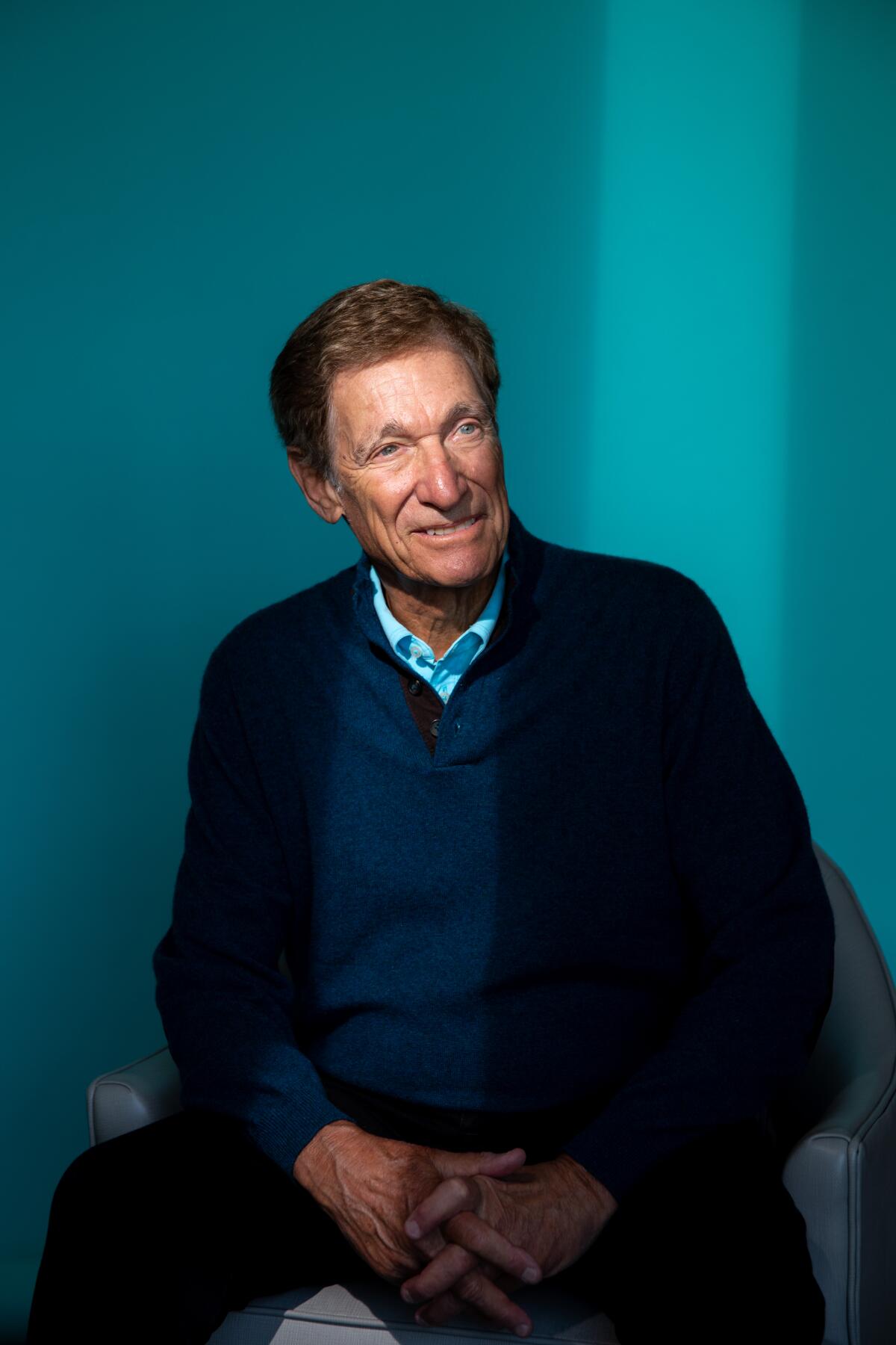 A portrait of Maury Povich in a dark sweater and jacket.