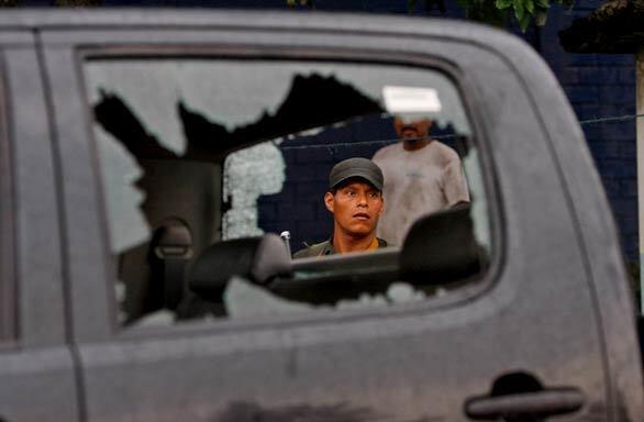 A soldier looks at a vehicle damaged during a shootout April 24 between anti-drug agents and alleged drug traffickers in Amatitlan, Guatemala, Five agents were killed.