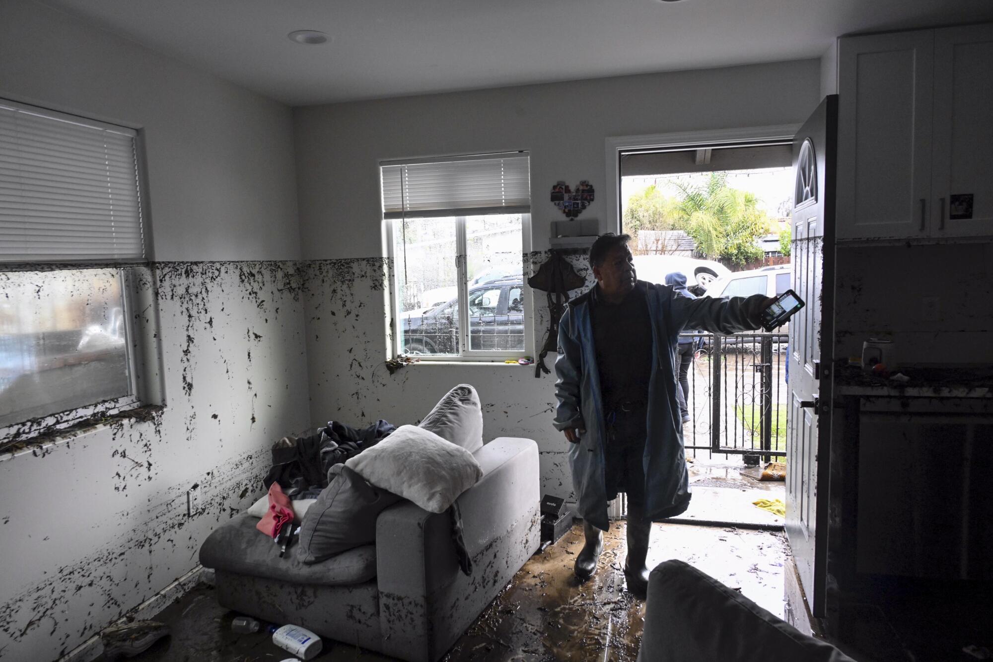 Tony Blas points to the water line inside his home that flooded during a rain storm in San Diego.