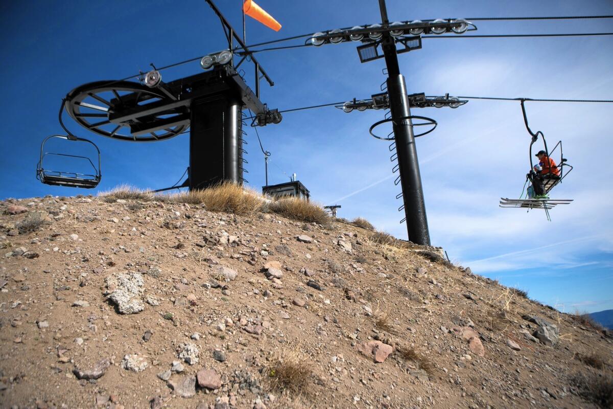 Skiers ride a chairlift over dry ground at Squaw Valley Ski Resort in March. Some Southern California ski resorts have closed early because of low snowfall.
