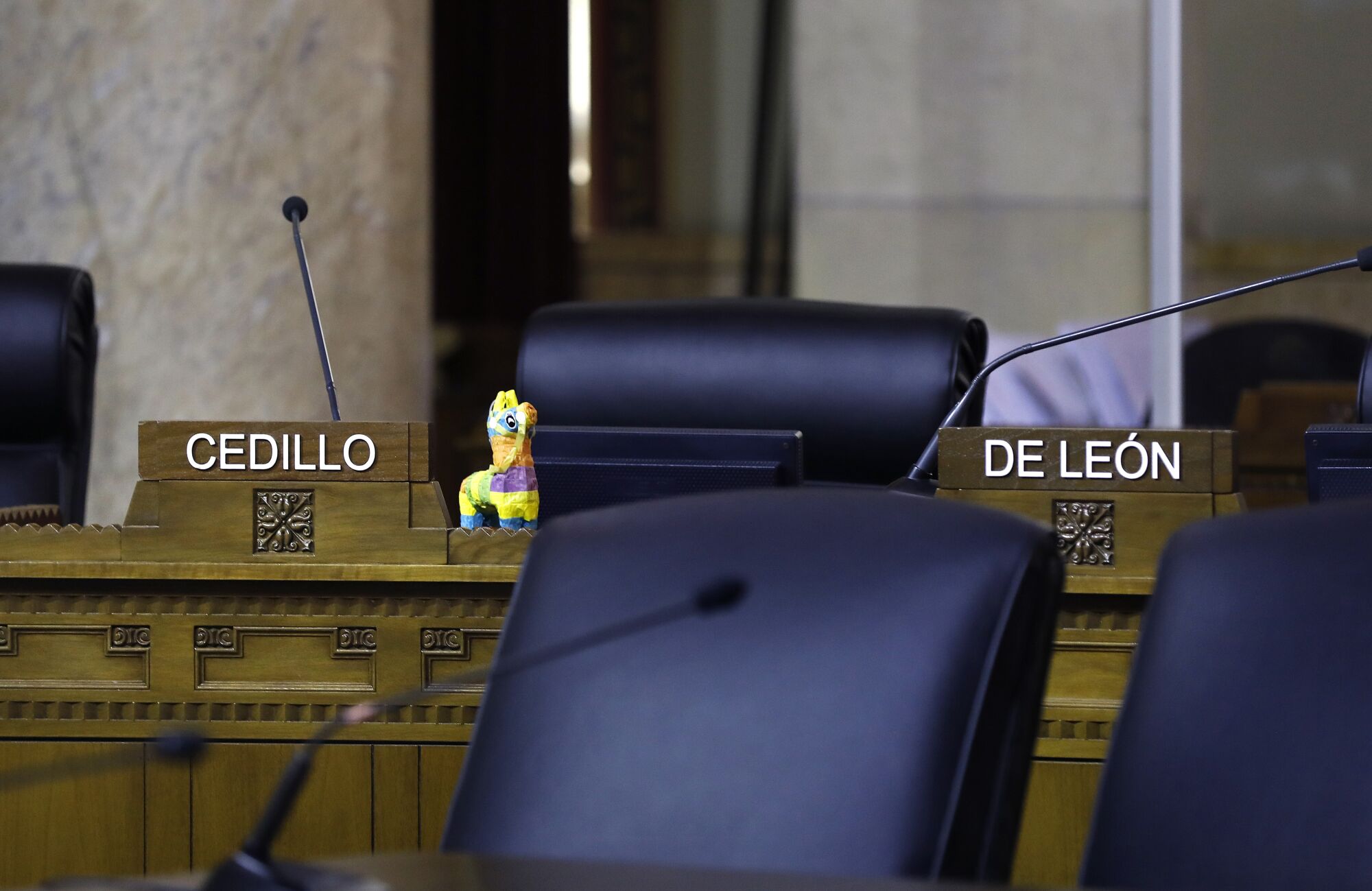 Chairs for Councilmembers Gil Cedillo and Kevin de León sit empty during a city council meeting. 