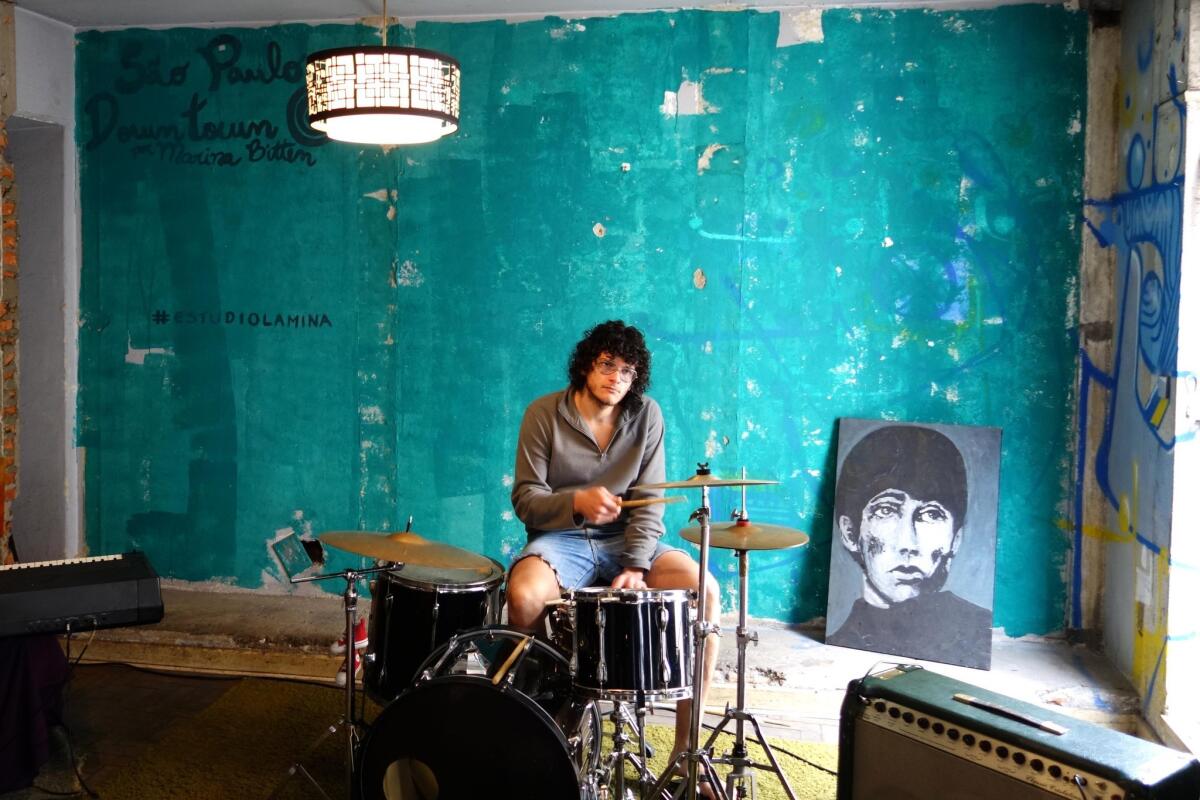Artist-musician Pe Boldaslove rehearses drumming in the Ouvidor 63 occupation, surrounded by recently completed works.