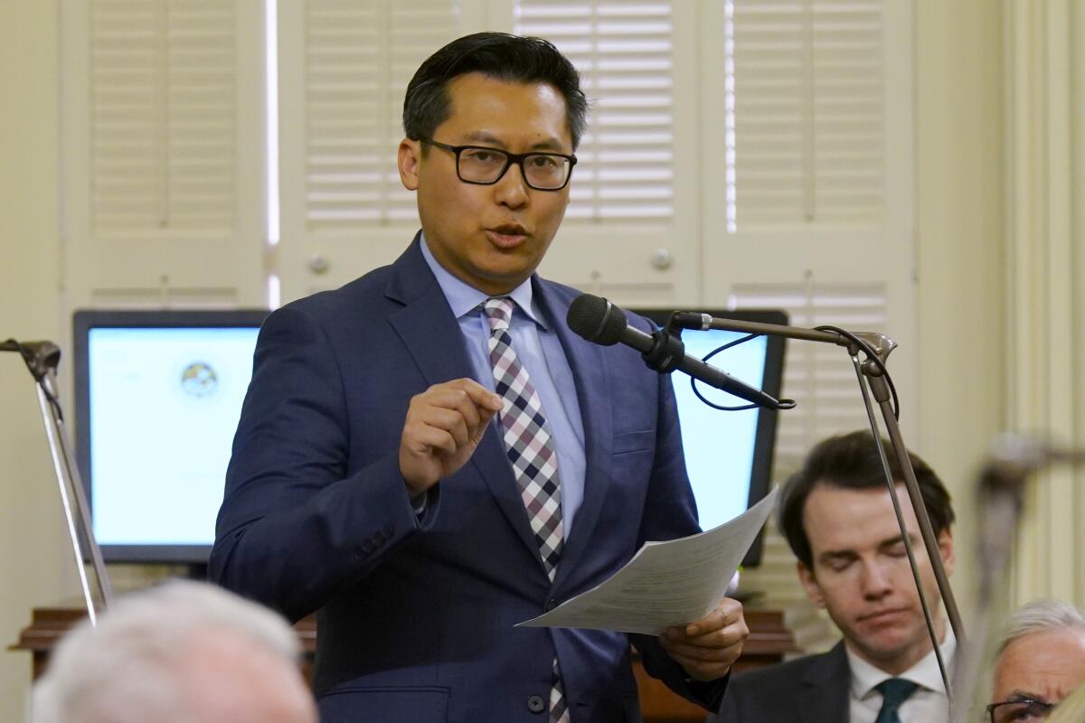 Assemblymember Vince Fong speaks at a microphone while holding papers.