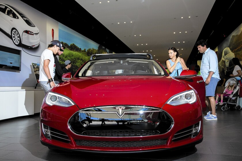 Nearly half of those getting state clean-vehicle rebates for Tesla's premium electric sedan earned at least $300,000 annually. Above, shoppers check out a Tesla Model S at a Santa Monica showroom.