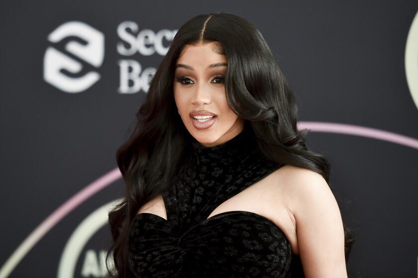 Cardi B posing in a black dress