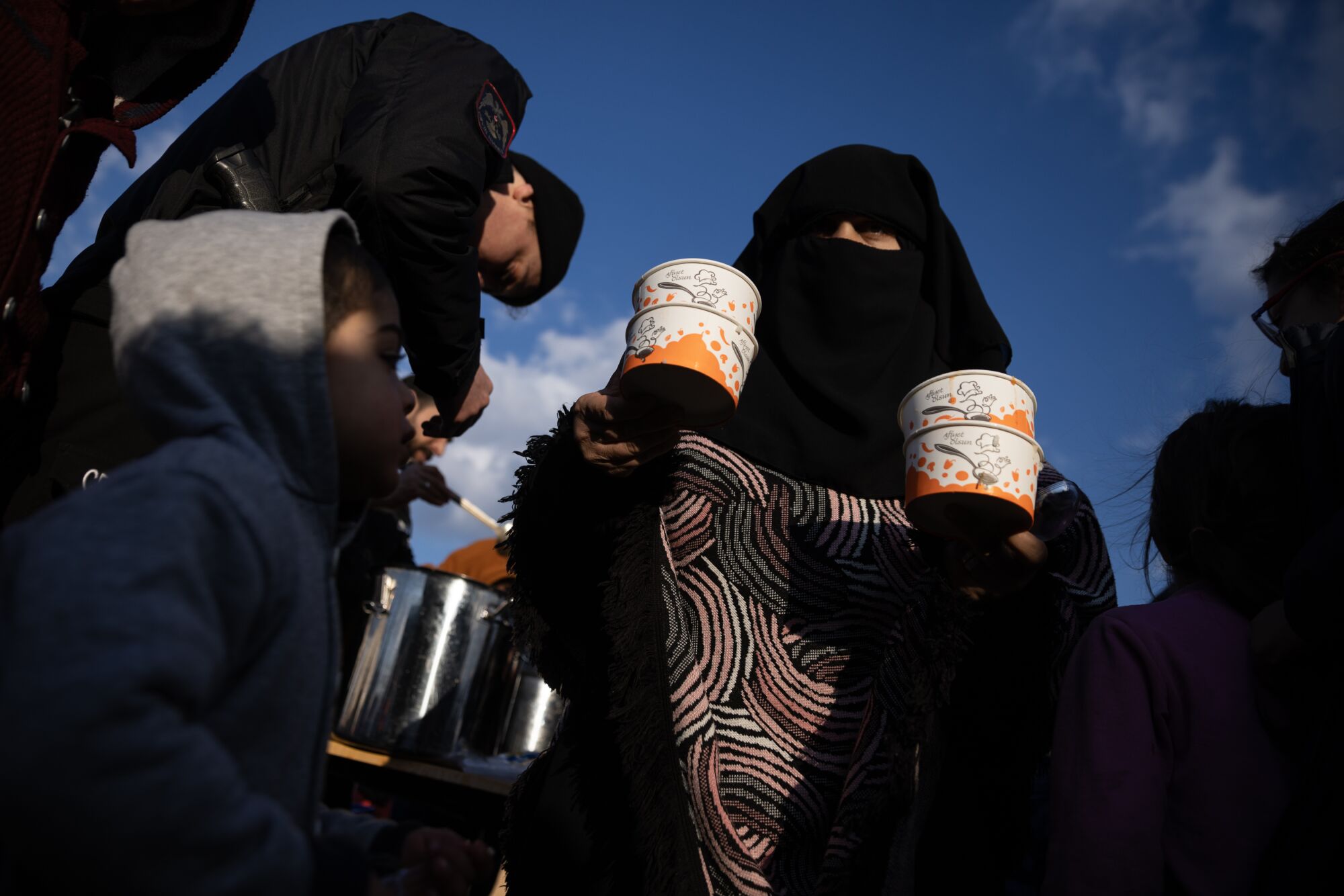 Displaced Syrians gather to receive food handouts at a makeshift camp in a sports centre near Kilis, Turkey