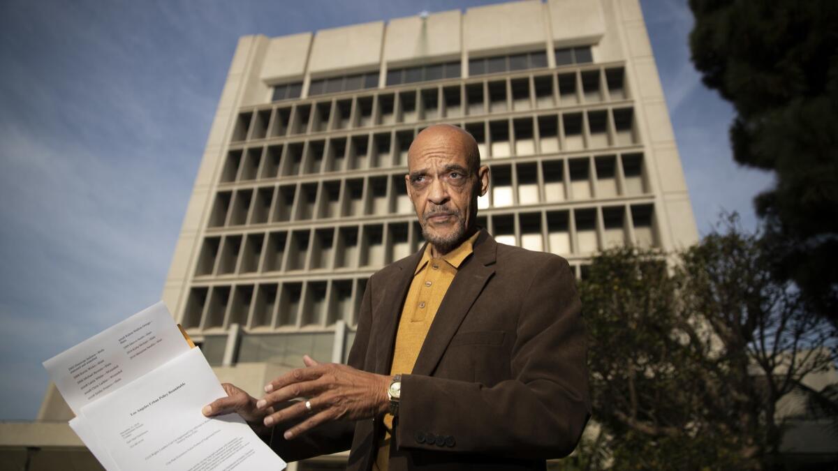 Longtime community activist Earl Ofari Hutchinson points to a list of people killed in encounters with Inglewood police while talking to reporters outside Inglewood City Hall on Sunday.