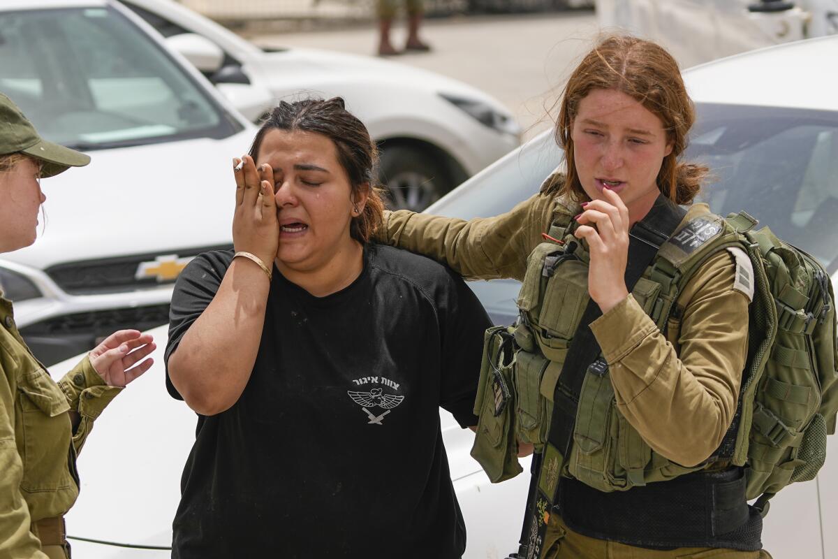 An Israeli soldier cries outside while another person offers comfort.