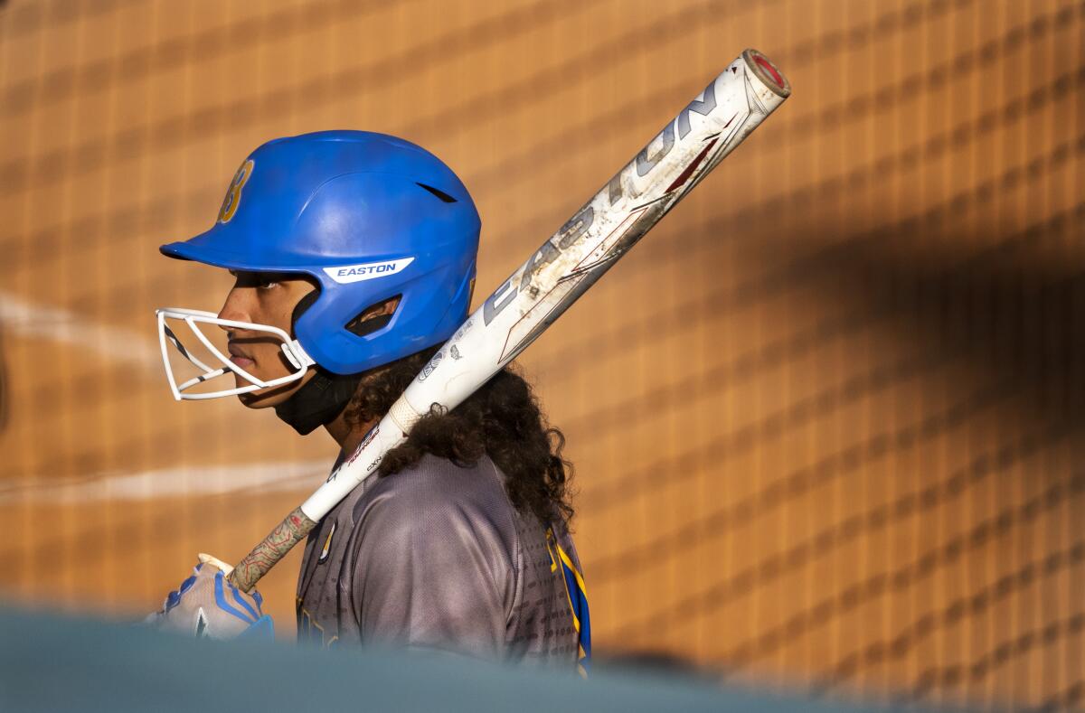 A softball batter waits her turn in the on-deck circle.