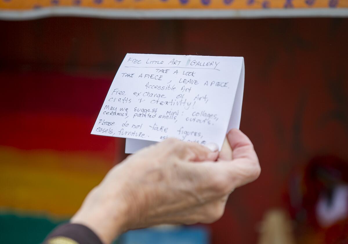 Charlene Ashendorf reads a note about the Free Little Art Gallery at her home in Costa Mesa.