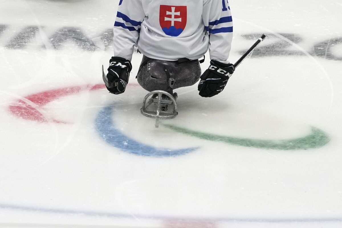 A Slovakian hockey player skates past the Paralympic logo during a practice session at the 2022 Winter Paralympics in Beijing, Thursday, March 3, 2022. In a stunning reversal, Russian and Belarusian athletes have been banned from the Winter Paralympic Games for their countries' roles in the war in Ukraine, the International Paralympic Committee said Thursday in Beijing. (AP Photo/Andy Wong)