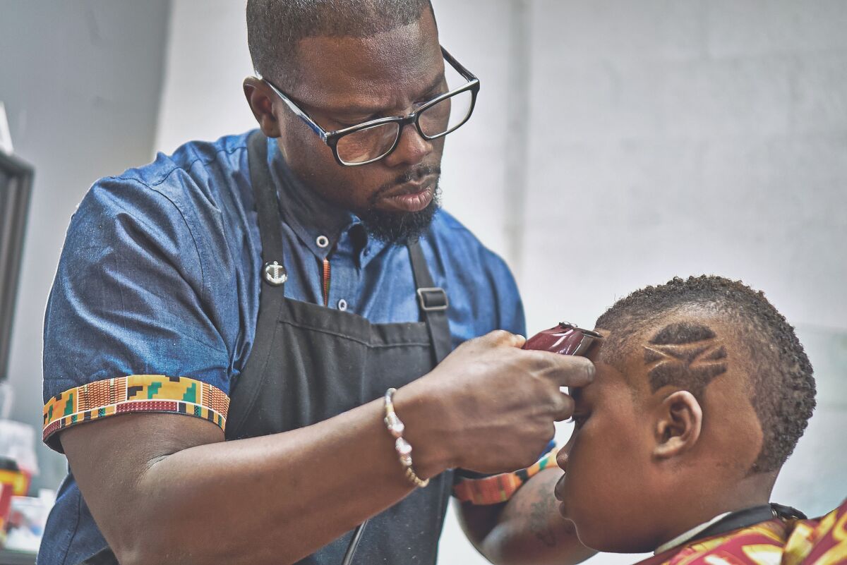 Kahlil Bryant, 41, does a fade haircut with design at his K-Cutz Barber Shop in San Diego, before he was forced to close the shop March 17 due to COVID-19 social distancing rules.