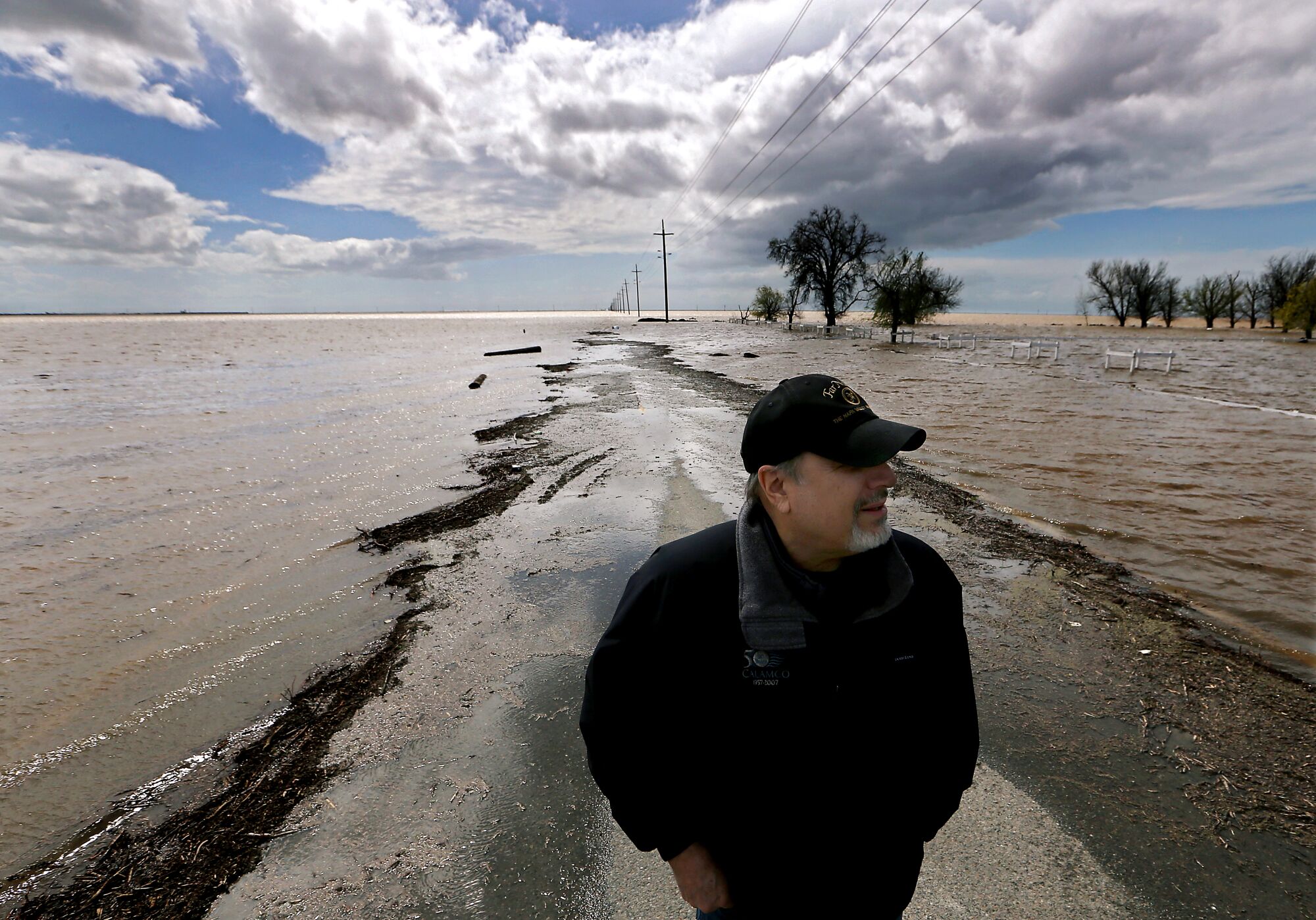 Mark Grewal, a farming consultant, stands on a flooded road near Corcoran.