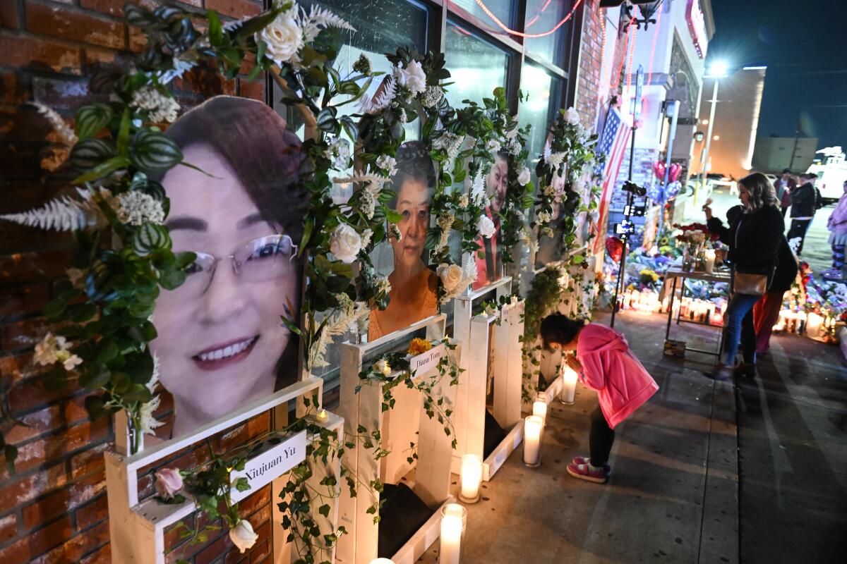 A girl bows at a series of portraits of victims of a mass shooting in Monterey Park.