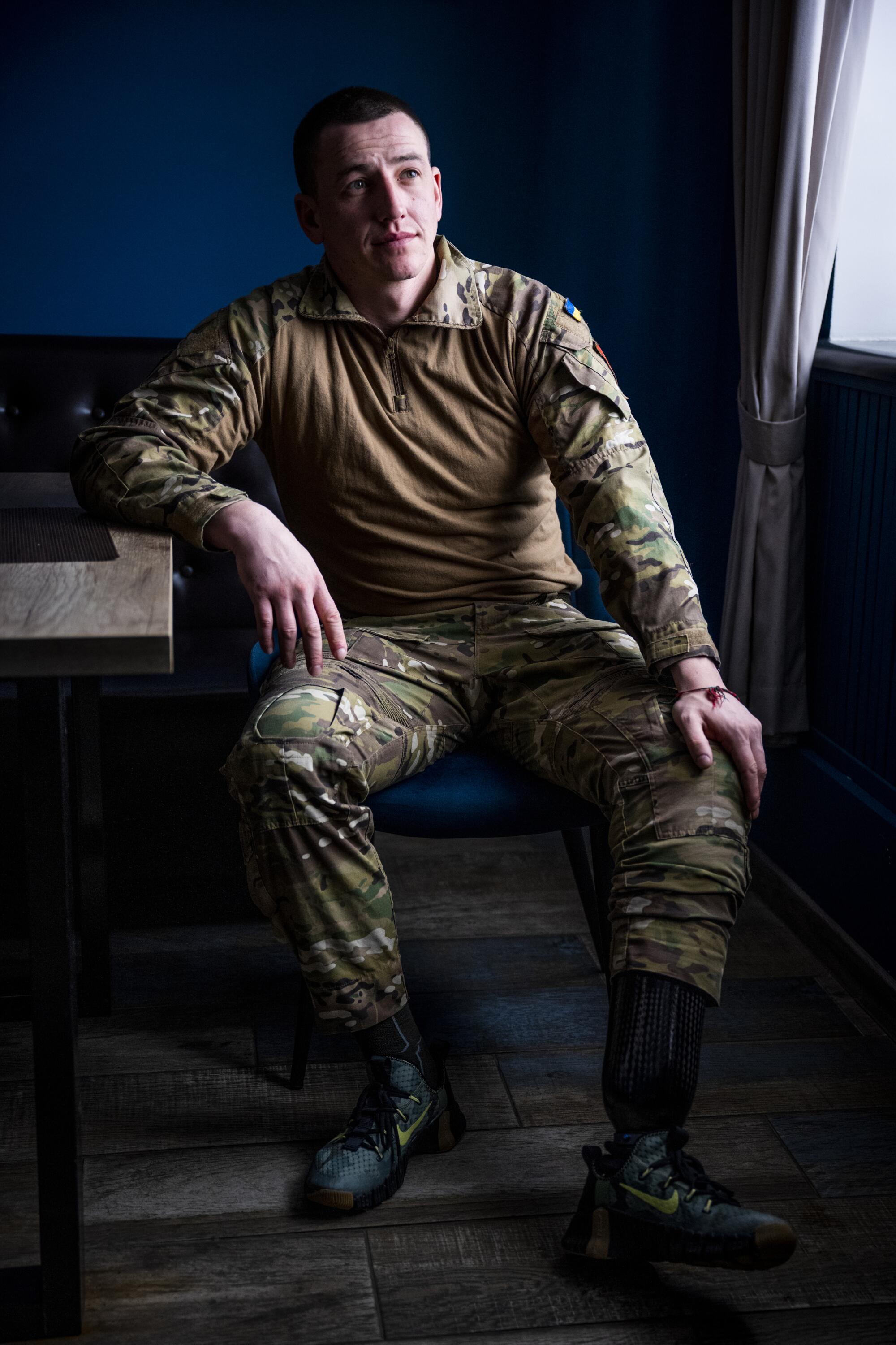 A portrait of a seated man in camouflage staring off into the distance  