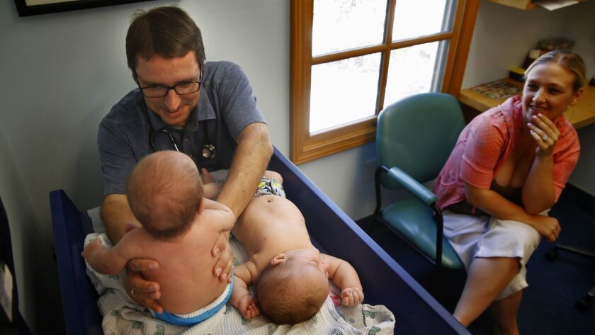 Dr. Bob Sears examines 2-month-old twins Andrew and William Sandoval in his office in 2014 as their mother, Karissa Sandoval, looks on. Among his many books on pediatrics, Sears has written "The Vaccine Book," in which he discusses his concerns about vaccines.