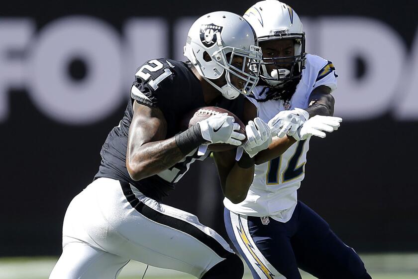 Raiders cornerback Sean Smith (21) intercepts a pass intended for Chargers receiver Travis Benjamin (12) during a game Oct. 9 in Oakland.