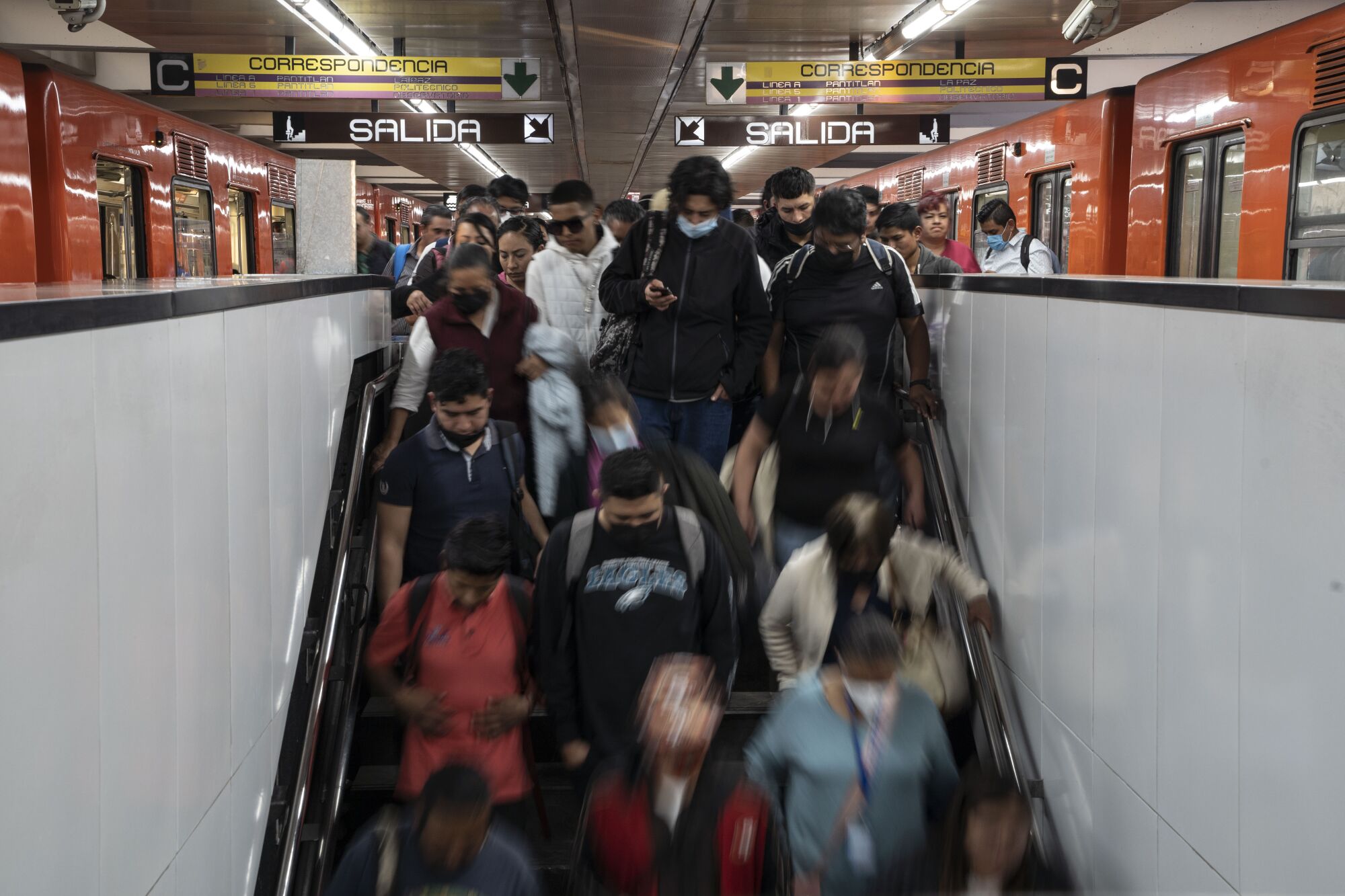 İnsanlar metro vagonları arasındaki bir merdiveni doldurup iniyor.
