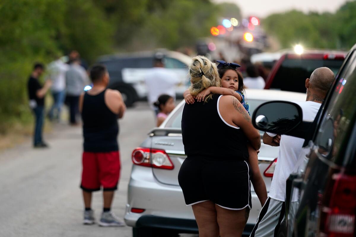 Onlookers stand near the scene where a semitrailer with multiple dead bodies was discovered, Monday, June 27, 2022