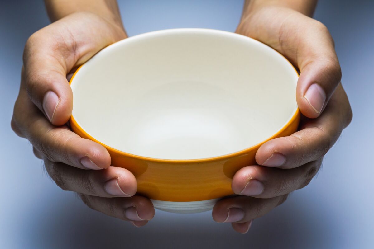 The hungry female holding an empty bowl on white background.