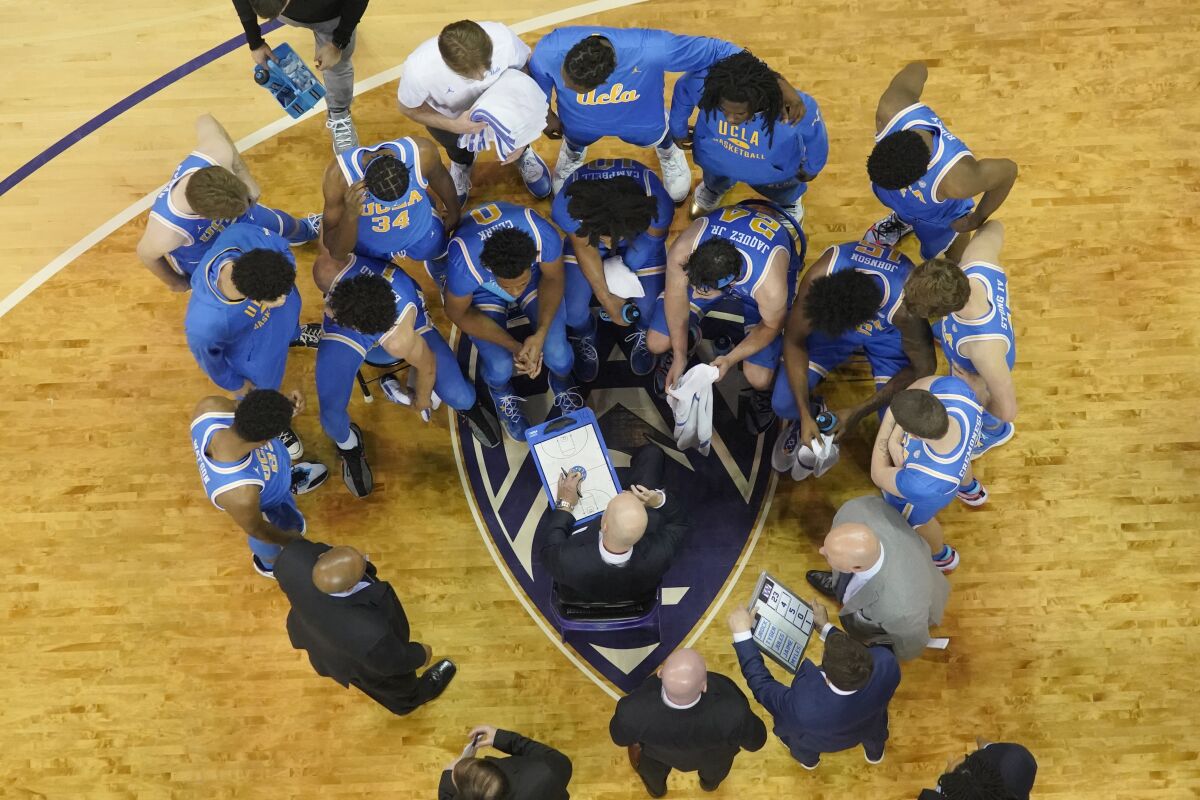 UCLA coach Mick Cronin, center, talks to his team during a time out in the second half against Washington on Monday.