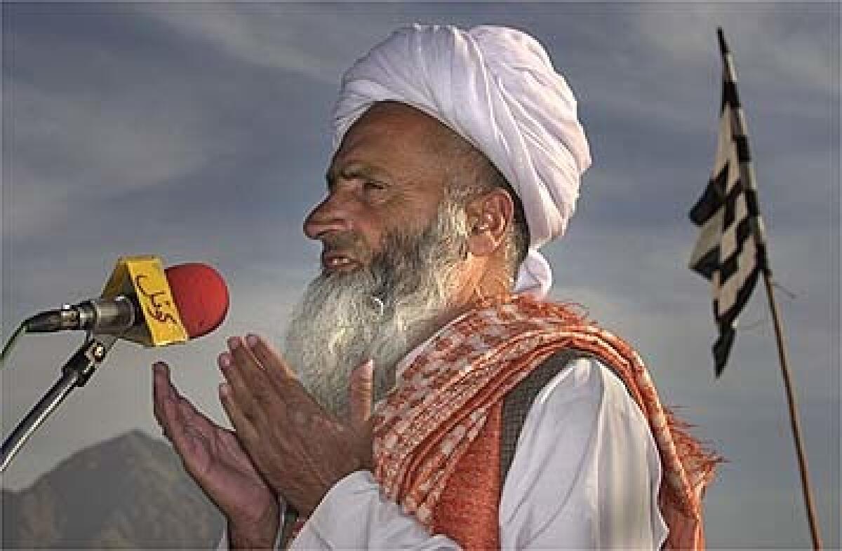 With white Taliban and striped party flags held by supporters, Maulana Noor Mohammed, right, prays at the stadium. His fundamentalist schools face closure or forced use of a secular curriculum.