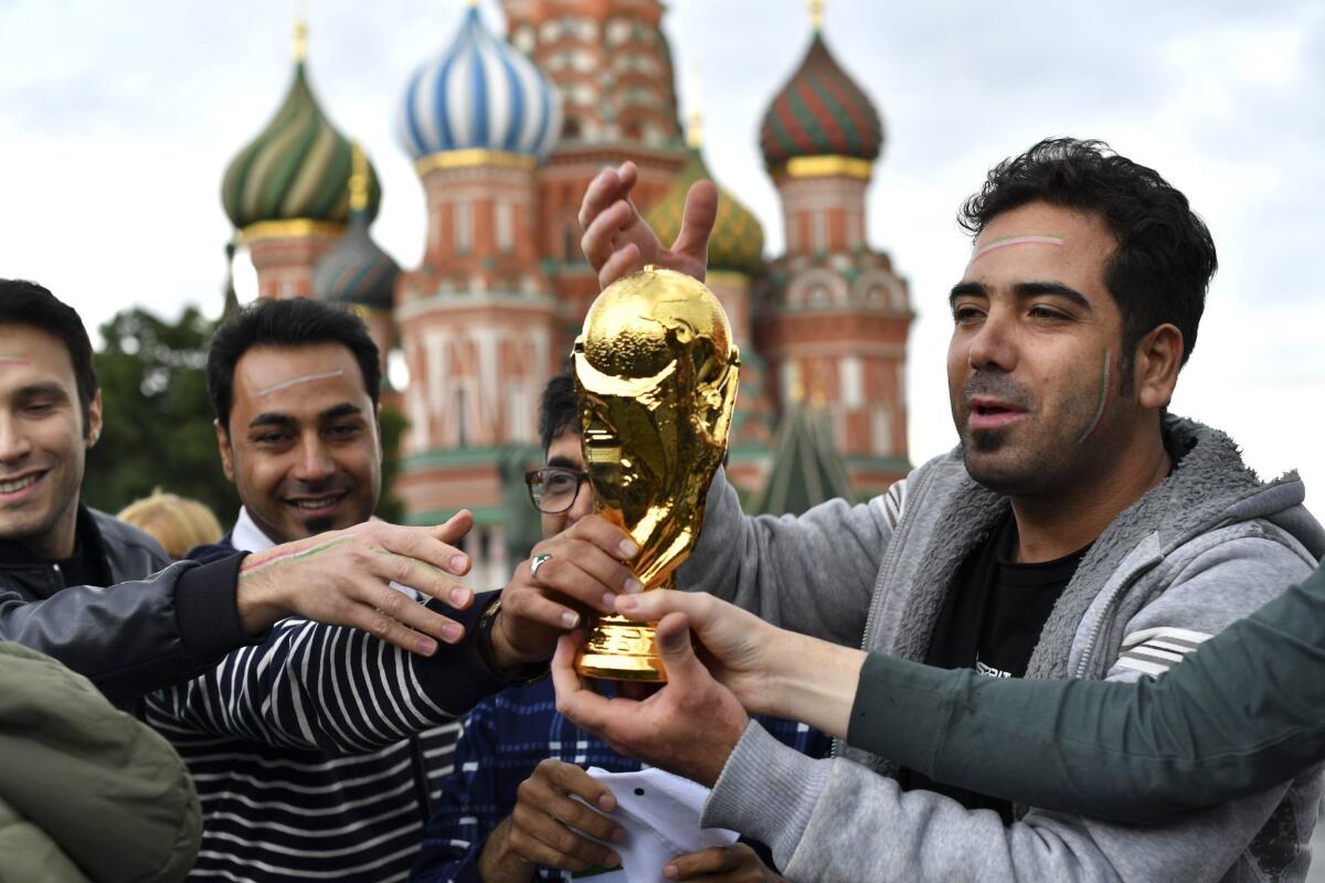 Iran's fans hold a fake trophy in front the Saint Basil's Cathedral on the Red Square in Moscow on June 10, 2018, ahead of the Russia 2018 World Cup.