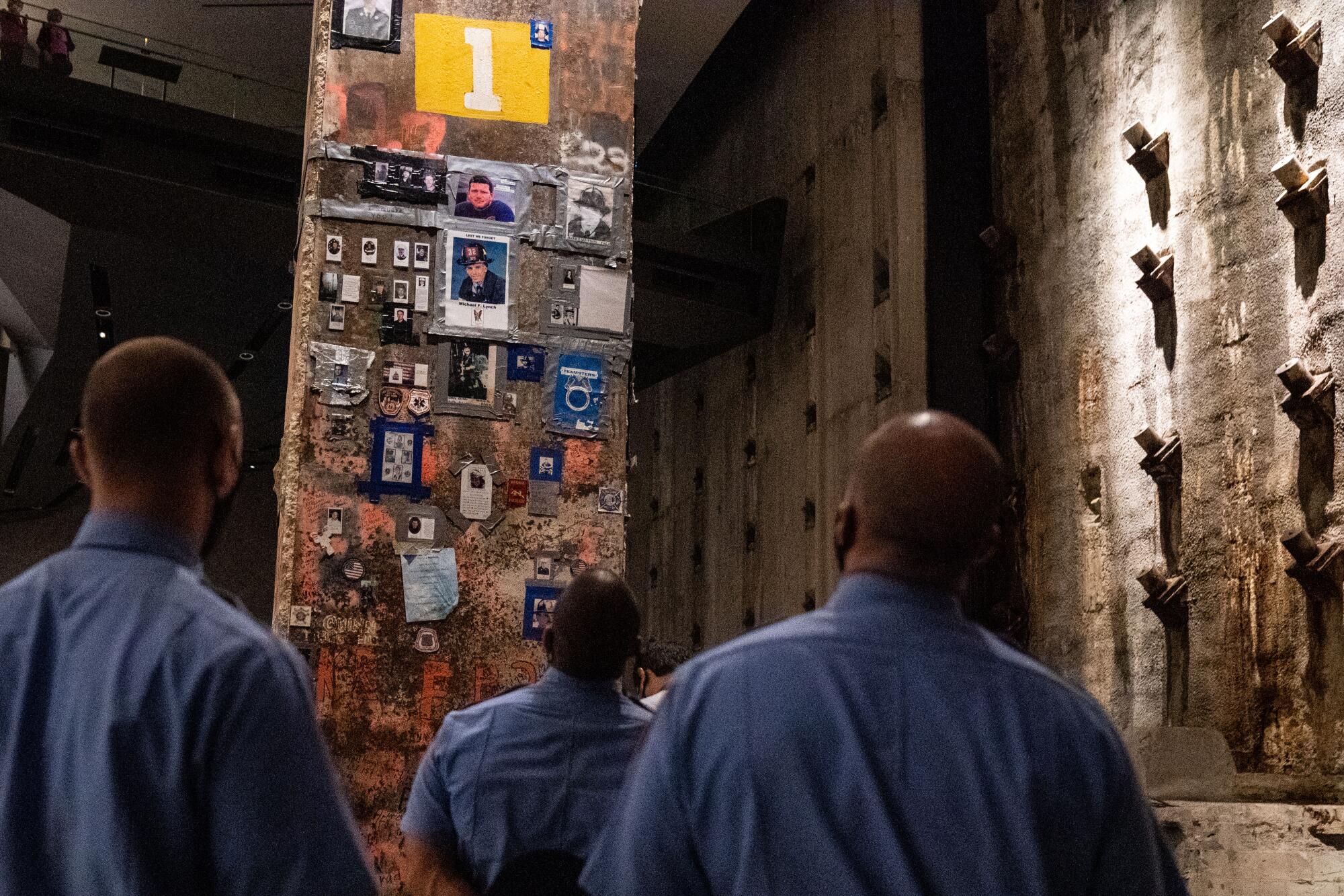 People look at photographs and other memorabilia attached to a column