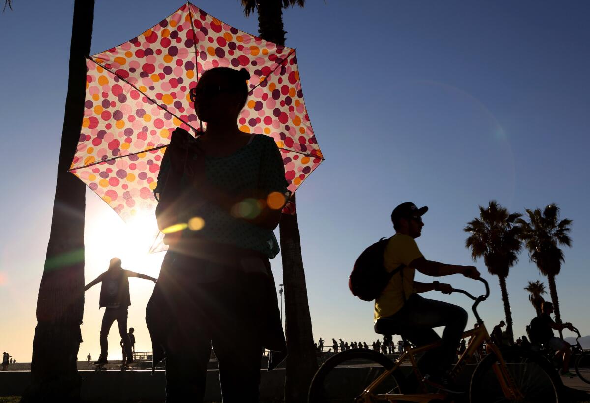Ariel Rhone uses an umbrella for shade near the Venice boardwalk.
