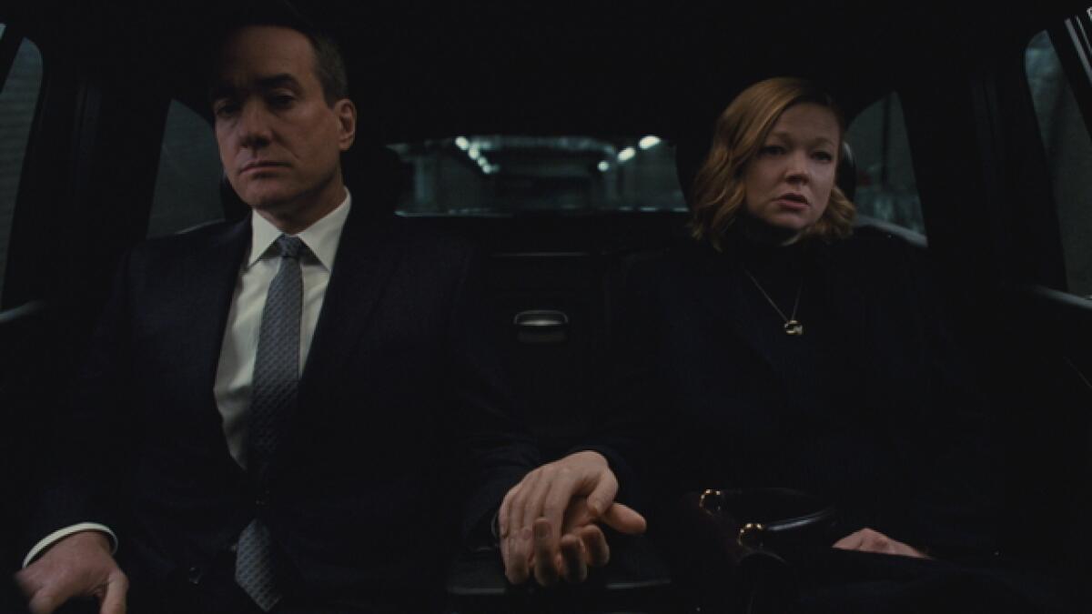 A husband and wife (Matthew Macfadyen and Sarah Snook), dressed all in black, coldly hold hands in the back of a town car.