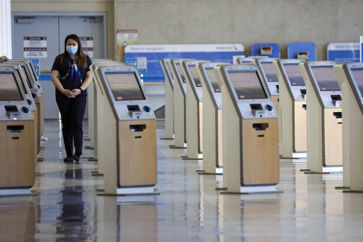 A worker with American Airlines stands among unused ticketing kiosks at Los Angeles International Airport in May.