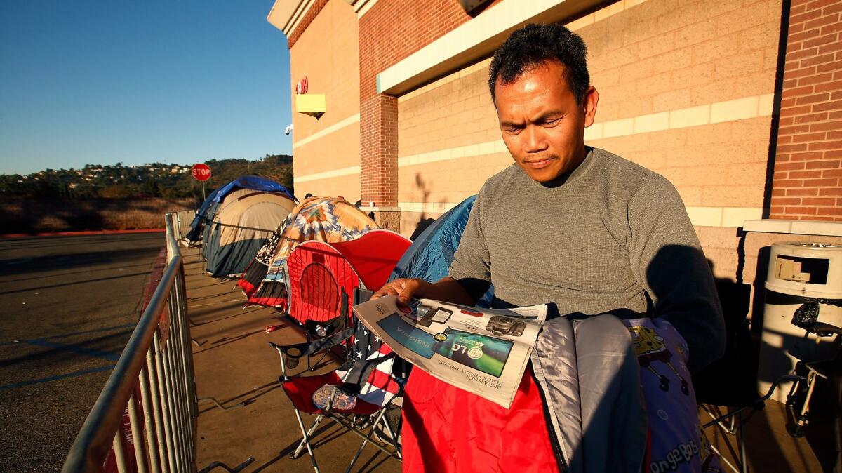 Jay Pujalte, a truck driver, looks at his newspaper advertisement for Black Friday "doorbuster" savings at the Best Buy store in Atwater Village, where he is camping out.