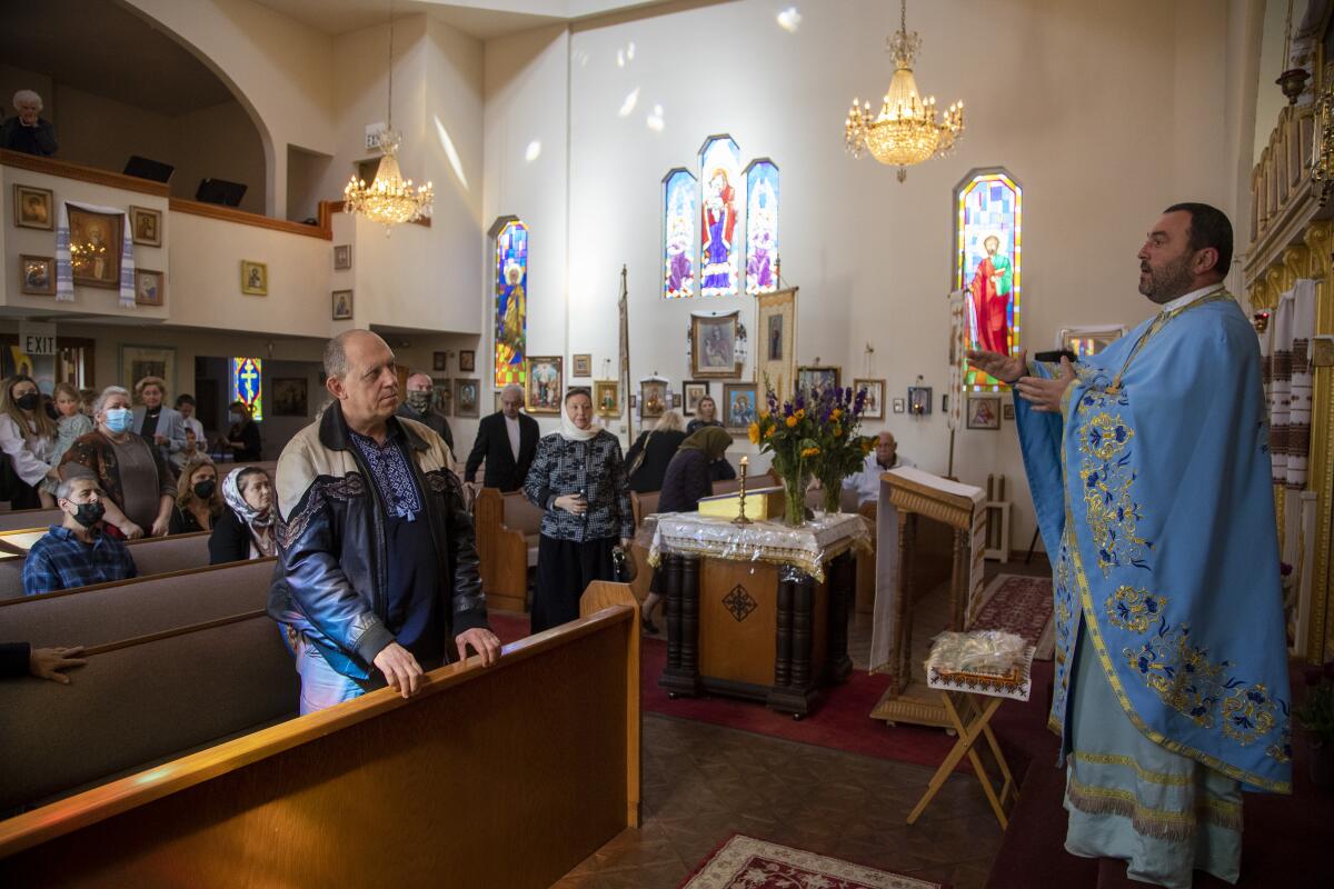 Father Vasile Sauciur, wearing robes, speaks to church members 