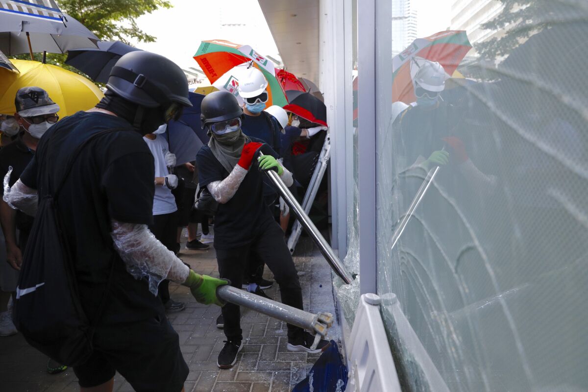 FILE - In this July 1, 2019, file photo, protesters try to break the glass walls of the Legislative Council in Hong Kong. From across the political spectrum, Hong Kong residents condemned mob violence at the U.S. Capitol, 18 months after they saw protesters storm their own local legislature. (AP Photo/Vincent Yu, File)