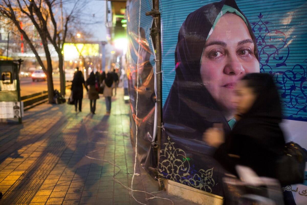 People pass electoral posters Thursday in downtown Tehran.